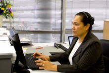 Akanesi Havea sits at her desk talking on a headset while typing on a keyboard