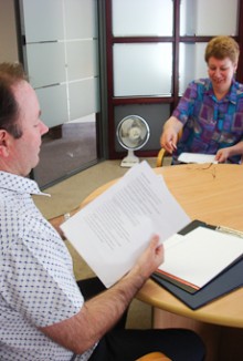 Sean Fitzgerald sits opposite a client, asking questions while referring to a folder