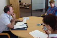 Sean Fitzgerald sits at a table having a meeting with two women