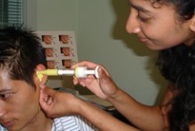 Renuka Foneska using an audiometry device in a client's ear
