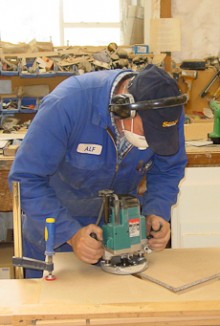 A cabinet maker uses a sanding machine on a piece of timber.