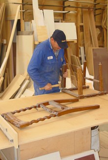 A cabinet maker assembles pieces of a chair.