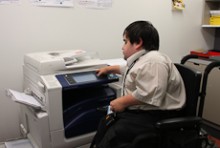 Peter Bradley adjusts the settings on a photocopier from his wheelchair