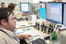 Peter Bradley at his desk with other contact centre workers in the background