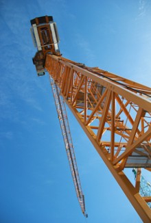 A tall tower crane against a blue sky
