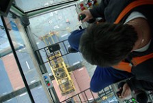 The view looking down through the glass floor-panel of a crane from behind the crane operator's head