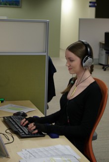 A court reporter sitting at a desk typing