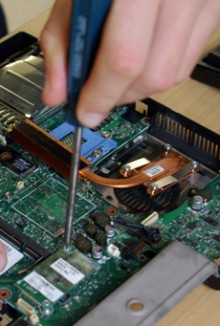 An electronics engineer unscrewing part of a circuit board