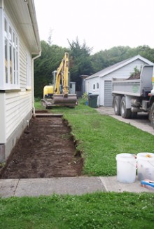 A digger digging up the soil around a house