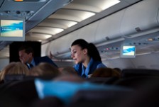 A flight attendant standing between rows of seats serving passengers