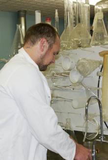 A forestry scientist standing at a sink with laboratory equipment.