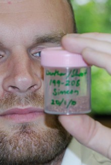 A close up picture of a forestry scientist looking at a sample in a container.