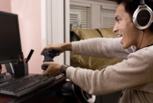 A game developer wearing headphones and holding a controller to test a computer game