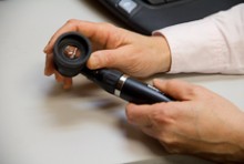 Hands holding an instrument for looking in a patient's ears