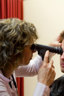 A general practitioner examining a patient's eye.