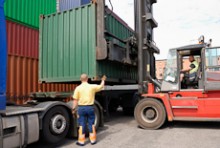 A forklift places a container on the back of a truck