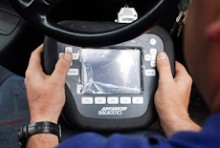 Close-up of a locksmith's hands holding an electronic key lock controller in a motor vehicle