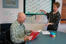 Robyn Pask standing by a year planner while her colleague sits at a table reading a book