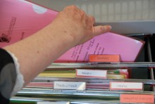 Hands reaching into a filing cabinet and bringing out a folder