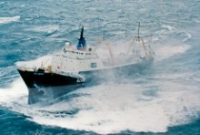 A fishing trawler crashing through waves at sea