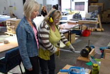 Mary Gibson stands next to a client who is gaining work experience in a factory