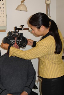 Marama Lambert adjusts eye testing equipment as a customer looks though it.