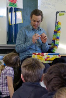 David Pierson sitting on a chair talking to a group of children sitting at his feet