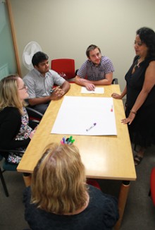 Kaushiki Roy standing at a table where a group of people are sitting