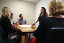 Kaushiki Roy standing at a table with a group of seated people around a sheet of paper