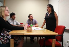 Kaushiki Roy standing up at a table with a group of people sitting round