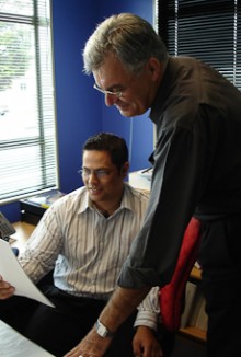Bruce Skinner talking with a colleague at his desk