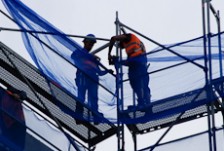 Two scaffolders installing scaffolding high on a building