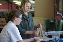 Sarah Carlton watches a student use a saw in a technology room