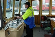 Paul Wilson standing at the wheel in the wheelhouse of his ferry