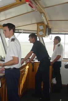 People in uniform standing at a ship's controls