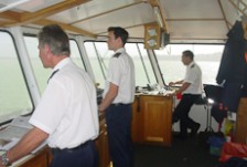 Several uniformed people standing at the controls of a ship