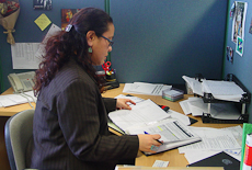 Janine Olasa sitting at her desk, looking at papers