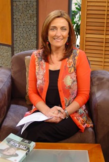 Lisa Manning sitting at a table, which has a book on it, smiling at the camera