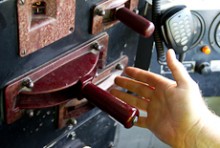 A hand reaching out to a large red lever in the driver's cab