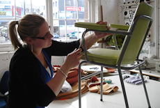 Nikki Burnet working on a chair which is on a workbench