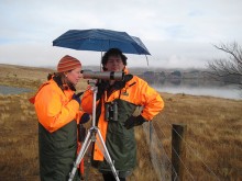 Jo Hoare looking through a telescope by a river with a colleague