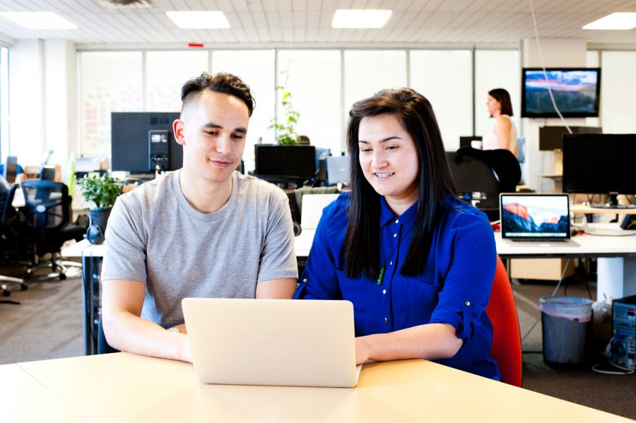 Two students study at a laptop on a desk