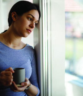 Sad young woman looking out window