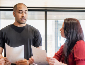 Two business people discuss reports they're holding