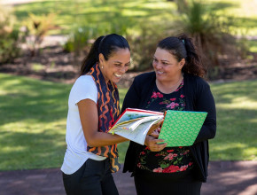 two women outdoors looking at a publication