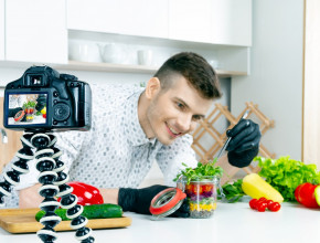 A kitchen chef has a video camera set up to film him styling colourful food jpg