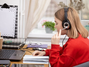 A teenager wearing headphones sitting at a desk at home 