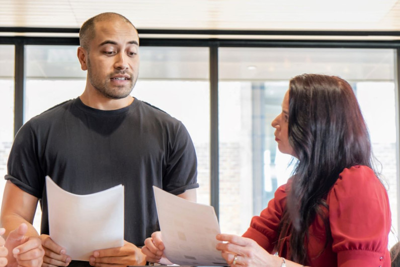 Two business people discuss reports they're holding