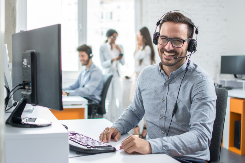 Man in call centre smiles at the camera