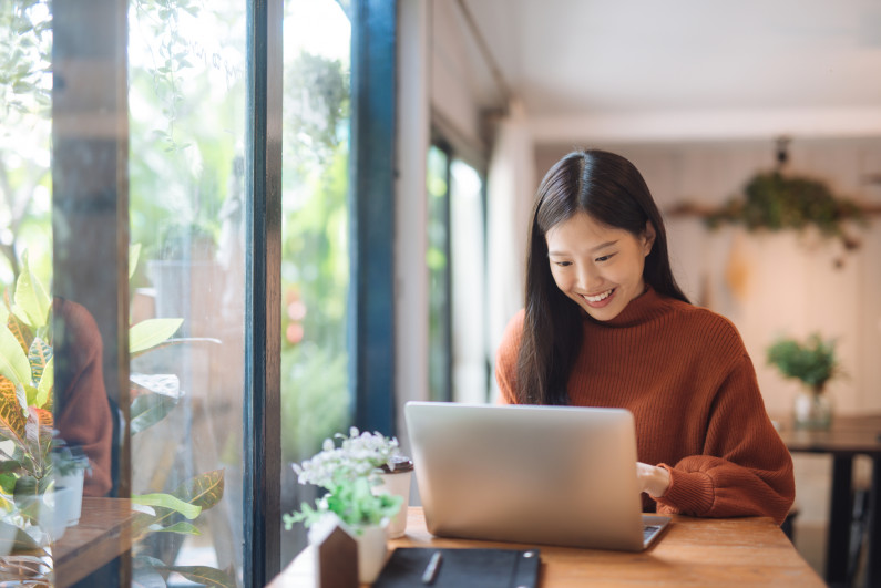 A woman sits at a cafe and does work on her computer